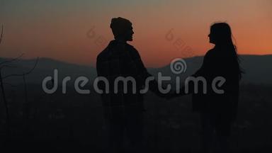 恋爱中的年轻夫妇在山上欣赏日落的<strong>剪影</strong>。 假期，旅行，浪漫，<strong>求婚</strong>